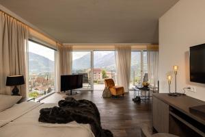 a bedroom with a bed and a large window at Hotel Finkenhof - Feel at home in Schenna