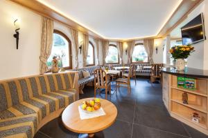 a restaurant with couches and a table and chairs at Hotel Garni Aghel in Selva di Val Gardena