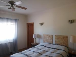 1 dormitorio con 1 cama y ventilador de techo en Chambres D'Hôte, en Bensafrim