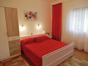 a bedroom with a red bed and a window at Apartment Ketty in Mošćenička Draga