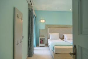 een slaapkamer met een bed met blauwe muren bij Villa Theodora View Apartments Eleni in Agios Georgios Pagon