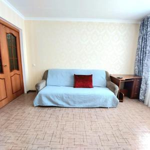 1 dormitorio con sofá azul y almohada roja en Аэропорт Астана 5 минут юг1 en Astaná