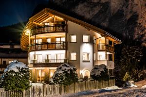 a building with lights on in the snow at Hotel Garni Aghel in Selva di Val Gardena