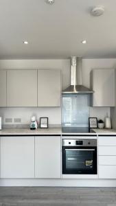 赫默爾亨普斯特德的住宿－Madison Court Apartments，厨房配有白色橱柜和炉灶烤箱。