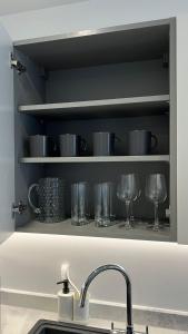 fregadero de cocina con vasos en un estante en Madison Court Apartments, en Hemel Hempstead