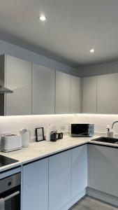 a kitchen with white cabinets and a microwave at Madison Court Apartments in Hemel Hempstead