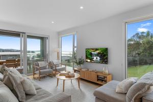 uma sala de estar com um sofá e uma televisão em Coastal Cool - Luxury Langs Beach Accommodation em Langs Beach