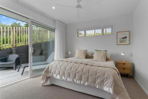 um quarto branco com uma cama e uma varanda em Coastal Cool - Luxury Langs Beach Accommodation em Langs Beach