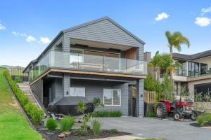 uma casa com um tractor vermelho estacionado em frente dela em Coastal Cool - Luxury Langs Beach Accommodation em Langs Beach