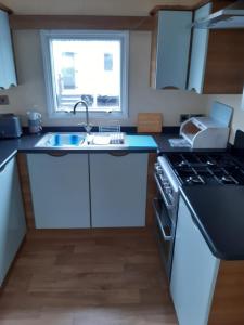 a kitchen with white cabinets and a sink and a window at Holiday caravan Trough of Bowland in Settle