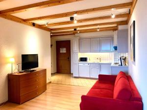 a living room with a red couch and a kitchen at Les Frênes in Leysin