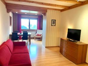 a living room with a red couch and a tv at Les Frênes in Leysin