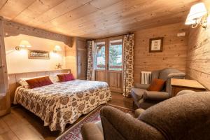 ein Schlafzimmer mit einem Bett und zwei Stühlen in einem Zimmer in der Unterkunft La Ferme du Var in La Clusaz