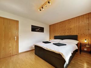 Chez Tonton في سيون: غرفة نوم بسرير كبير وبجدار خشبي