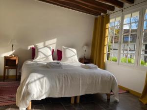 a bedroom with a bed with white sheets and a window at Une Vie en Rose in Pressagny l'Orgueilleux