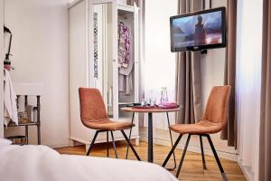 ケルンにあるHotel am Chlodwigplatzの椅子2脚、テーブル、テレビが備わる客室です。