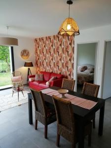 a living room with a table and a red couch at Charmante Maison neuve au Lac d'Hourtin in Hourtin