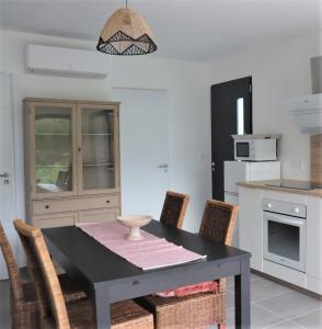 a kitchen with a black table and chairs in a kitchen at Charmante Maison neuve au Lac d'Hourtin in Hourtin