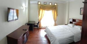 a bedroom with a bed and a dresser and a window at Flamboyan House in Padang