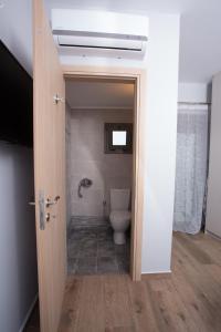 a bathroom with a toilet and a door open at Lux Aprt in a Graphical Village in Kerásia