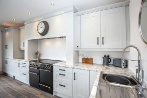uma cozinha com armários brancos e um relógio na parede em 4 Bedroom Barn conversion in Beamish County Durham em Durham