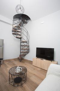 a living room with a spiral staircase and a television at Lux Aprt in a Graphical Village in Kerásia