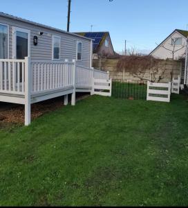 a house with a white fence and a yard at The Ruby Lido Beach Prestatyn in Prestatyn