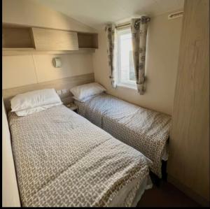 two beds in a small room with a window at The Ruby Lido Beach Prestatyn in Prestatyn