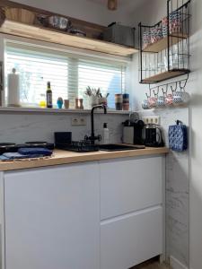 a kitchen with white cabinets and a sink and a window at Appartement 't Loft in Zandvoort