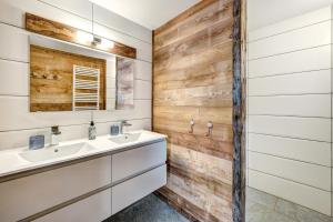 a bathroom with two sinks and a wooden wall at LA FERME de BELLINE Chalets ou Gîtes & SPA in Briançon