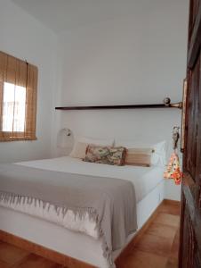 a white bedroom with a bed and a window at Casa Mocan in Arrecife