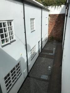 an alley between two white buildings with windows at West Street Mews - Serviced Accommodation in Exeter