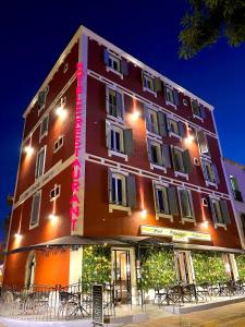 un grand bâtiment rouge avec des tables devant lui dans l'établissement Hotel Restaurant Christophe Colomb, à Calvi