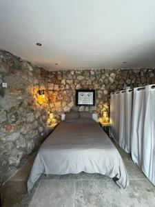 a bedroom with a large bed in a stone wall at Jolie maison avec vue sur piscine in Bouc-Bel-Air