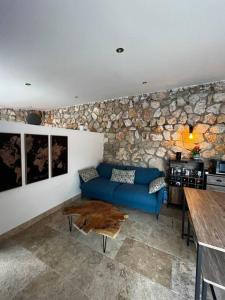 a living room with a blue couch and a stone wall at Jolie maison avec vue sur piscine in Bouc-Bel-Air