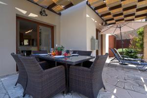 una mesa con sillas y una sombrilla en el patio en 3 bedroom Villa Athina with private pool and golf views, Aphrodite Hills Resort en Kouklia