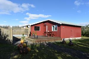 Cabaña roja con terraza de madera en un patio en Laxás Cottage, en Blönduós