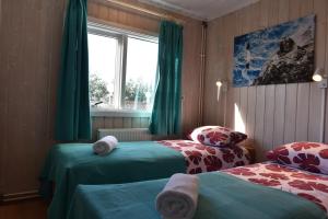 a bedroom with two beds with green curtains and a window at Laxás Cottage in Blönduós