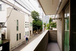 a woman walking down a street with an umbrella at 新宿顶级奢华三层独栋别墅/车站5分钟/儿童房/8人 in Tokyo