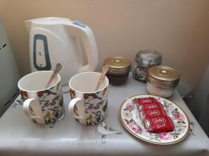 un mostrador con dos tazas y un plato de comida en Cotswold Cottage Bed & Breakfast, en Luckington