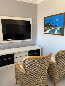 uma sala de estar com 2 cadeiras e uma televisão de ecrã plano em Apartamento enseada Guarujá no Guarujá