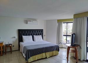 a bedroom with a large bed and a television at PRAIA DE MUCURIPE - FRENTE MAR - Ap205 in Fortaleza