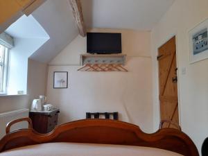 a bedroom with a bed and a tv on the wall at Cotswold Cottage Bed & Breakfast in Luckington