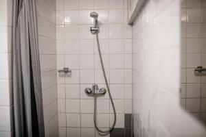 a shower with a hose in a white tiled bathroom at Diek 27 Farmhouse in Den Hoorn