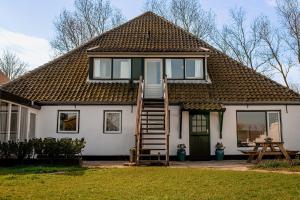 a small white house with a staircase leading up to it at Diek 27 Farmhouse in Den Hoorn