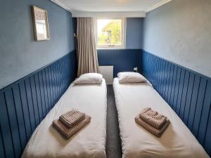 two beds in a small room with a window at Diek 27 Farmhouse in Den Hoorn