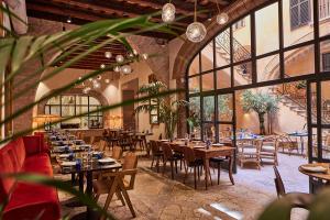 ein Restaurant mit Holztischen, Stühlen und Fenstern in der Unterkunft Puro Grand Hotel in Palma de Mallorca