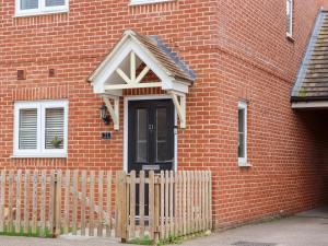 een stenen huis met een zwarte deur en een houten hek bij Bridgefield House in Ashford