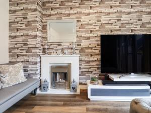 een woonkamer met een open haard en een televisie bij Bridgefield House in Ashford