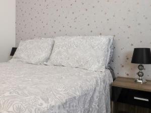 een bed met een wit dekbed en een tafel met een lamp bij Bridgefield House in Ashford